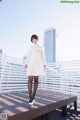 A woman in a white coat standing on a wooden platform.